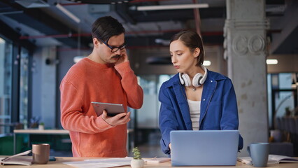 Two managers looking solutions for hard business task at coworking office.