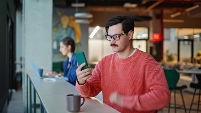 Satisfied guy tapping smartphone in modern coffee shop closeup. Smiling man