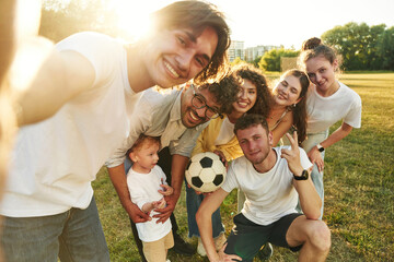 Selfie time, smiling. Young friends are having fun on the field with soccer ball