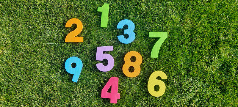 Mixed digits one to nine in bright colors on green grass field for kids activities, classroom materials, educational math design and fun learning