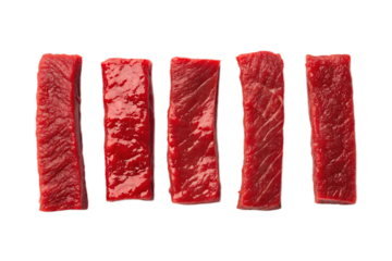 Five strips of raw red meat arranged in a row on a black background in a studio setting view from above