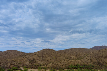 Arid desert mountains with sparse vegetation stretch across landscape in Sunflower, Maricopa County rolling hills dramatic cloudy of Arizona desert