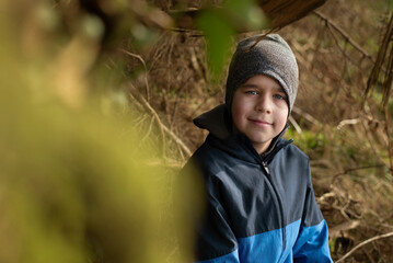 A young boy walks through the forest, resting in the shade of tree after training with his father in the forest, they ran, played football, did push-ups