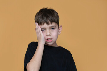 A young boy in black shirt rests his face in his hand, conveying tiredness or boredom. The young boy is very tired from many tasks at school, and from training and playing musical instruments