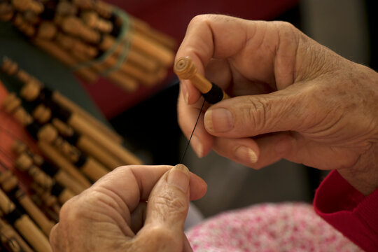 Detail of the hands of a traditional bobbin lacemaker performing her craft.