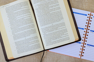 An open Bible book sits next to planner on desk, creating thoughtful environment for organization, study.