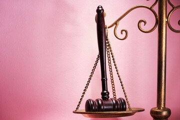 libra scale and gavel hammer against pink background.