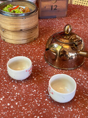 tea set with pot and dim sum tray on red cement table