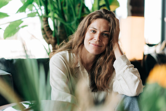 Portrait of a tender relaxed red-haired freckled woman sitting looking at the camera.