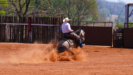 cowboy riding a quarter horse and doing a bump maneuver on a sand track