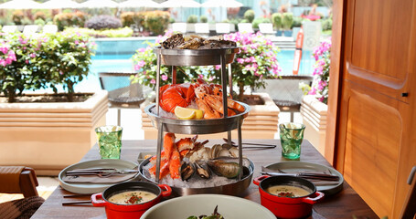Luxurious seafood platter by poolside, featuring oysters, shrimp, crab. Summertime outdoor dining, perfect for gourmet food promotions. Vibrant, fresh, elegant setting.