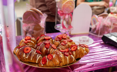 Close-up of a plate of delicious sweet croissants with berry strawberry sprinkles and chocolate, sweet food and coffee