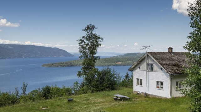 White house in a meadow, view opens onto Lake Mj&oslash;sa or Mjosa and forested mountain ridges, Olavsweg or Olavsleden, near Tangen, Norway