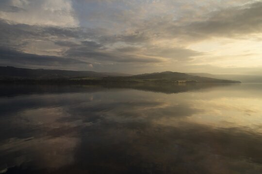 The sky and clouds are reflected on the surface of Lake Mj&oslash;sa or Mjosa just in front of sunset, near Hamar, Norway