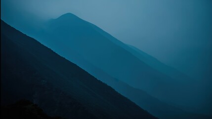 Fototapeta premium A peaceful wilderness scene at dusk, with a mountain range silhouetted against a sky of deep twilight blue.