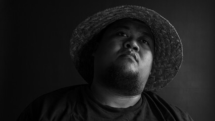 Man wearing straw hat looking upward, black and white portrait style, isolated concept of hope, dream, imagination, vintage photography aesthetic for artistic use.