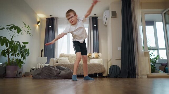 Boy performing handstand in bright living room with cozy sofa, bean bag, wooden floor, potted plants and natural daylight, showing playful childhood energy, balance, sport, fun and freedom indoors