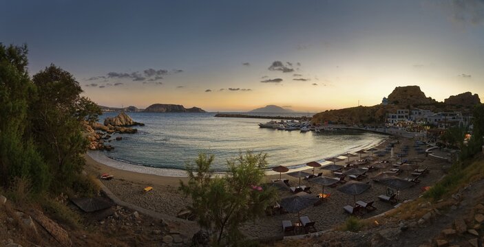 Beach of the fishing village Finiki with parasols and the sea in a quiet evening mood, Finiki, Karpathos, Greece