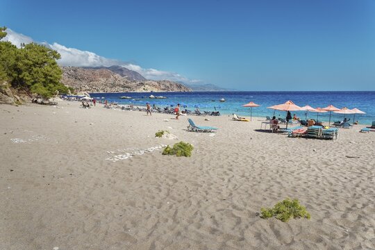 Scenery of sunny Apella beach with deckchairs by the sea, Apella beach, Karpathos, Greece