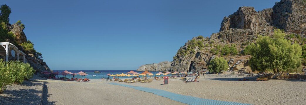 Wide view of the quiet Ahata beach with parasols and blue sea in the background, Ahata Beach, Aperi, Karpathos, Greece