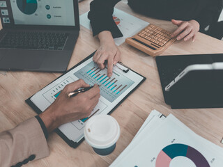 Colleagues analyzing data on documents and digital tablet at workplace Two business men working on a laptop and digital tablet with financial charts, graphs and data in the office