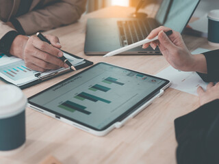 Colleagues analyzing data on documents and digital tablet at workplace Two business men working on a laptop and digital tablet with financial charts, graphs and data in the office