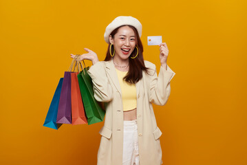 Smiling Asian woman holding colorful shopping bags and showing credit card consumer lifestyle online payment holiday sale promotion and digital finance concept