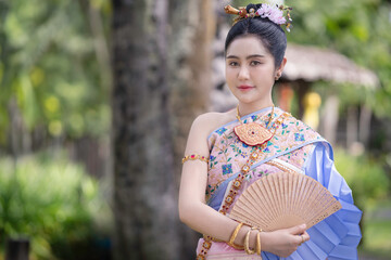Pretty Asian Thai woman wearing traditional Thai dress costumes according to Thai culture at the ancient temple in famous tourist attraction in Thailand.