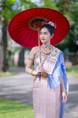 Pretty Asian Thai woman wearing traditional Thai dress costumes according to Thai culture at the ancient temple in famous tourist attraction in Thailand.