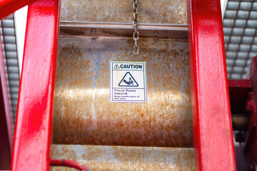 "Pinch point warning sign" hand and finger injury prevention alert that showed on the industrial equipment such as blender, pumping or milling machine. Safety sign in unsafe working place, close-up.
