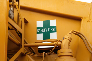 "Safety first" warning sign on the crane vehicle or industrial machine part. Safe working practice with risk condition. Close-up with selective focus.