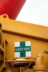 "Safety first" warning sign on the crane vehicle or industrial machine part. Safe working practice with risk condition. Close-up with selective focus.