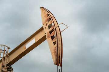 Beam pump or Donkey pump operating to recovered crude oil from the production oil well, with cloudy sky background. Industrial with technology scene.