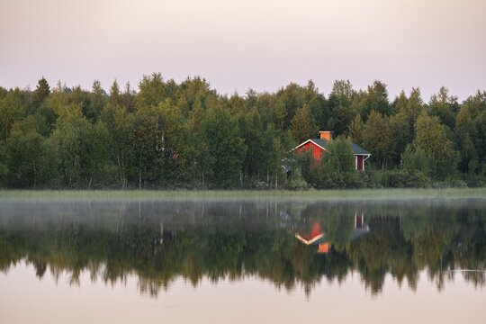 Red hut reflected in lake, Muonio, Lapland, Finland