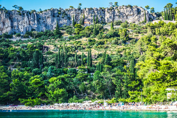 Kašjuni Beach in Split with sea, green trees, and mountain layers, Croatia