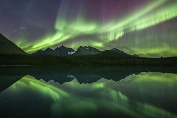 Northern lights over the mountains of the Lyngen Alps, reflection in lake, Lyngen, Norway