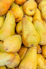 A pile of ripe juicy yellow pears displayed for sale on a supermarket vegetable counter. Demonstration of organic vegetarian and healthy food. Close-up