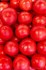 Close-up of many bright fresh tomatoes in a grocery store. Pyramid of juicy pink tomatoes in a crate