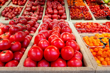 Red tomatoes are lying in transparent trays on the shop counter. Tomato theme background