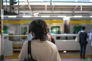 People standing in line at a Japanese train station platform, waiting for a subway train to arrive. Urban transportation, daily commuting, and modern lifestyle concept in Tokyo, Japan
