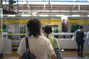 People standing in line at a Japanese train station platform, waiting for a subway train to arrive. Urban transportation, daily commuting, and modern lifestyle concept in Tokyo, Japan
