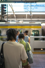 People standing in line at a Japanese train station platform, waiting for a subway train to arrive. Urban transportation, daily commuting, and modern lifestyle concept in Tokyo, Japan
