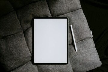 Naklejka premium A tablet computer with a stylus rests on a dark gray quilted cushion