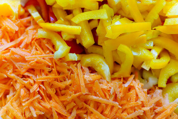 Freshly prepared shredded carrots and yellow peppers in a colorful salad bowl ready for serving