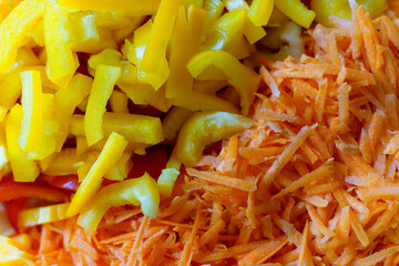 Freshly chopped yellow peppers and grated carrots for healthy meal prep in a kitchen setting