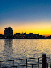 Fototapeta premium A tranquil urban sunset view with a colorful sky over the city skyline and reflections on the calm harbor water
