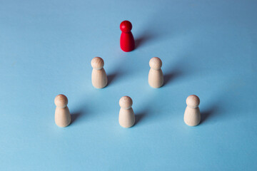 Red wooden figure leading team pyramid on blue background