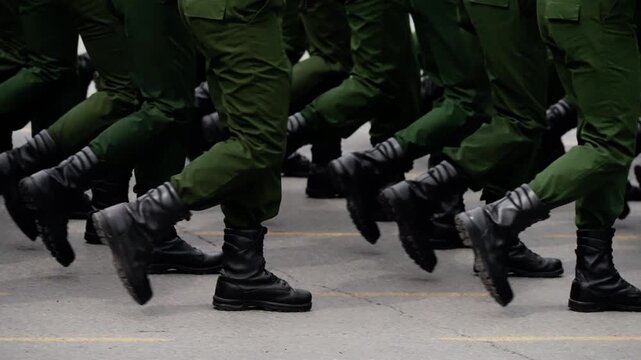 Close-up of uniformed soldiers marching in formation, black combat boots striking pavement in synchronized cadence, highlighting discipline, coordination, and drill precision.