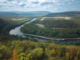 Experience the stunning aerial hyperlapse of the Potomac River winding through Berkeley Springs, framed by lush greenery and rolling hills in West Virginia.
