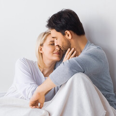 Square image - tender kissing couple with closed eyes, lying lay in bedroom bed together. Blonde woman, brunette bearded man at home. Love, relationship, happy family, dating, tenderness concept.